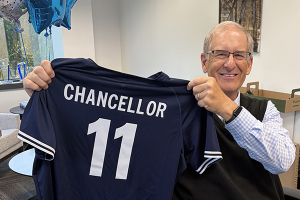 Chancellor Jeff Pittman holds a branded STLCC jersey celebrating 11 years of service.