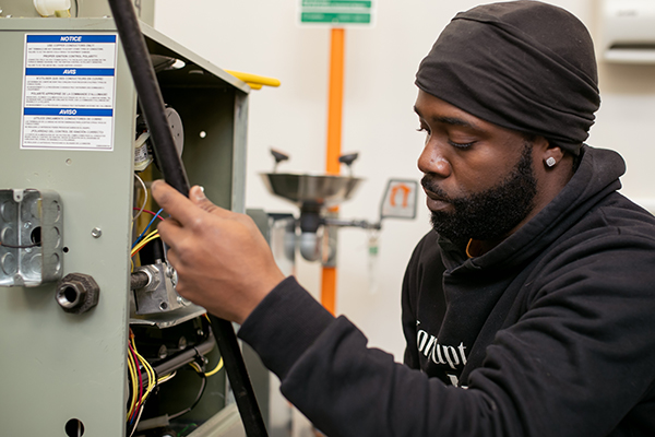 Student working with industrial machinery in a training lab.