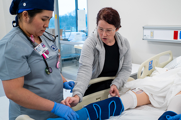 Nursing instructor and student practice a patient care technique in an STLCC nursing lab.