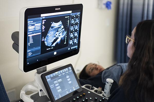 Student training to become a sonographer using ultrasound equipment in a lab width=