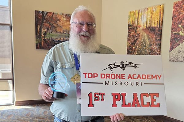 Chuck Wivell, an STLCC remote aircraft pilot student, holds a first-place sign after winning a drone photo contest at Top Drone Academy. width=