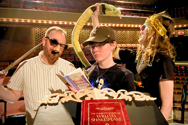 Cast members pose with props for STLCC-Forest Park’s production at the Mildred E. Bastian Center for the Performing Arts width=