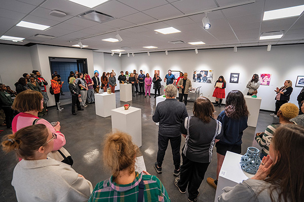 visitors viewing student paintings and drawings at STLCC exhibition width=