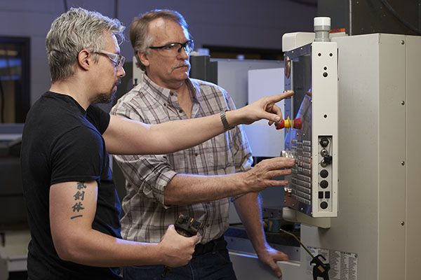 Student receives guidance from instructor during a manufacturing course