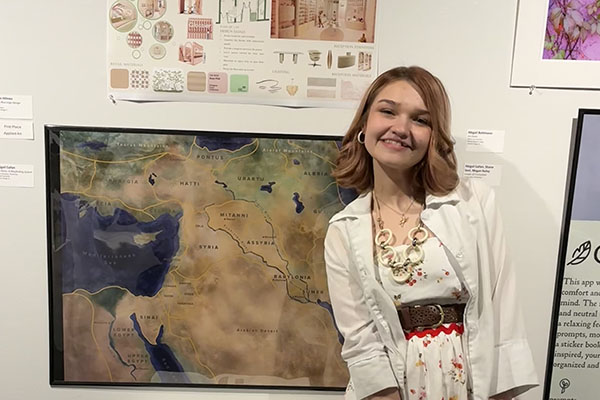 Abigail Bohlmann posing in front of her design work