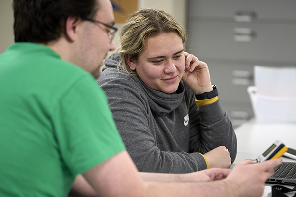 STLCC student sitting with a tutor at a table, reviewing notes and discussing coursework, representing academic support and success. width=