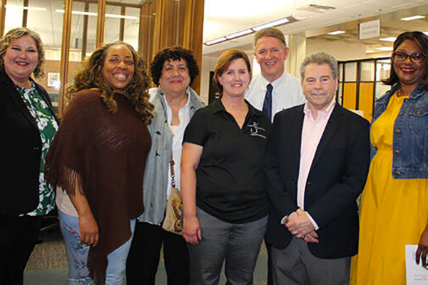 From left to right, Elizabeth Gassel Perkins, EdD, campus president, is joined with Marie McCool, theatre manager and the 49th David L. Underwood Memorial Lecture Award recipient, in the black shirt, past Underwood award recipients, and McCool’s husband Vic, second row.