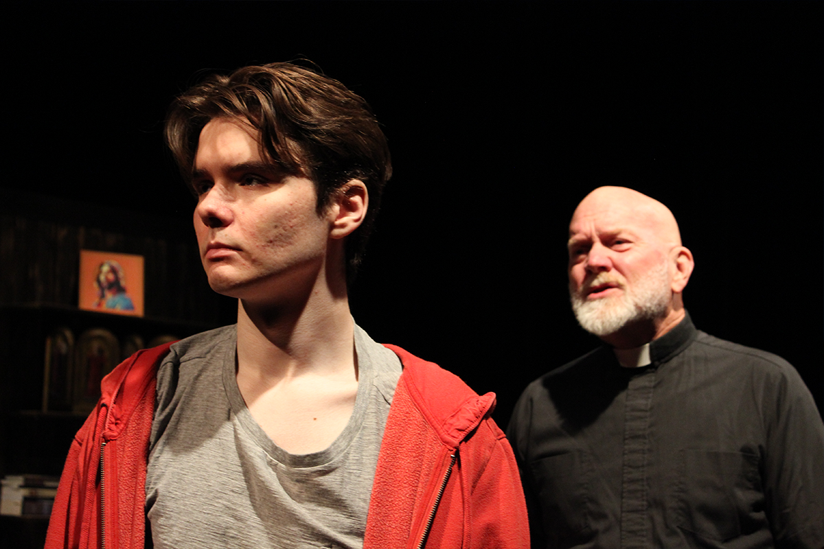 Concerned priest looking at pensive boy in red hoodie