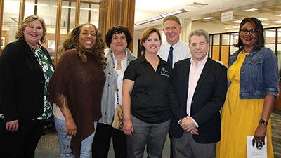 From left to right, Elizabeth Gassel Perkins, EdD, campus president, is joined with Marie McCool, theatre manager and the 49th David L. Underwood Memorial Lecture Award recipient, in the black shirt, past Underwood award recipients, and McCool’s husband Vic, second row. 