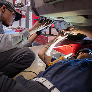 Students working underneath a car