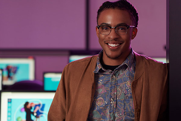  Student smiling in front of classroom filled with computers