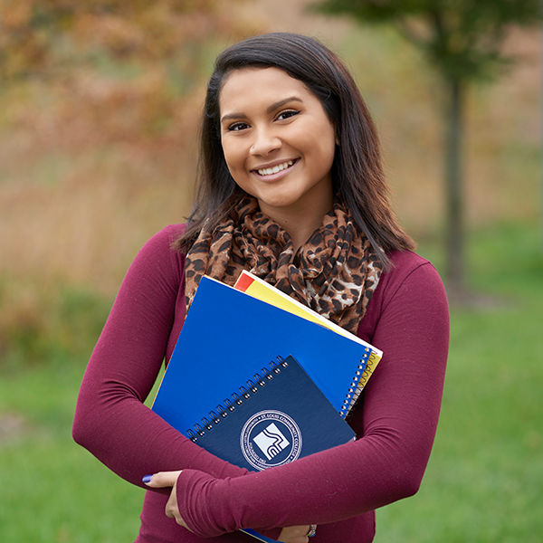 female student outside wildwood campus holding books